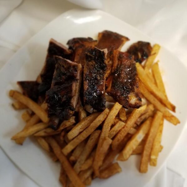 A plate of food with french fries and ribs.