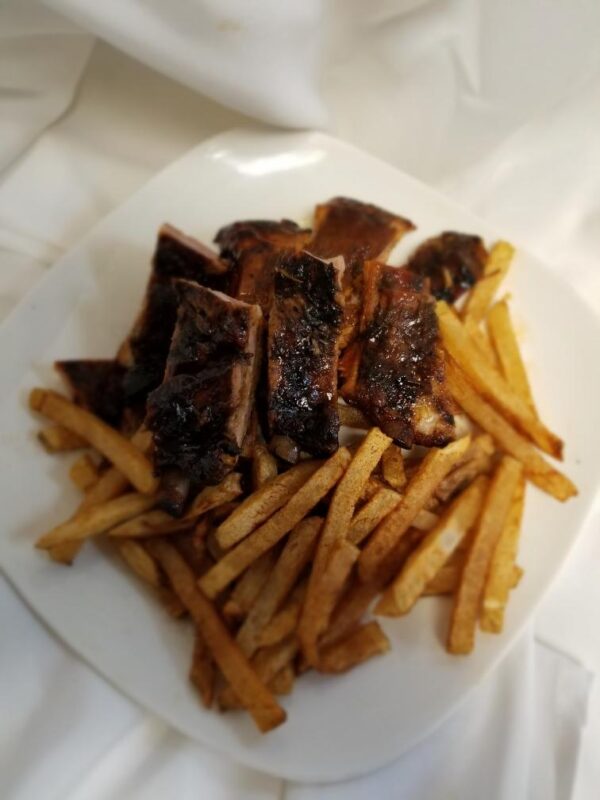 A plate of food with french fries and ribs.