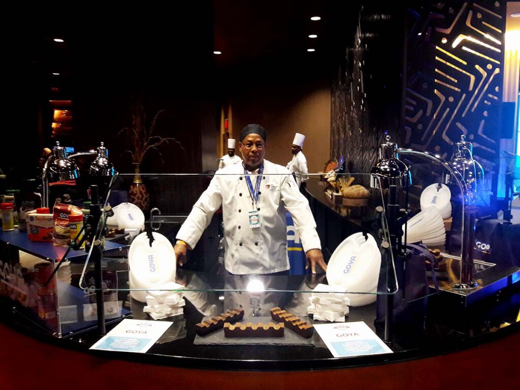 A man standing in front of some food on top of a table.