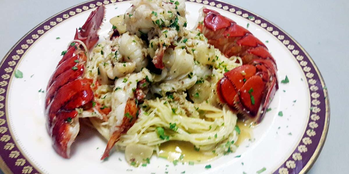A plate of lobster and pasta with sauce.