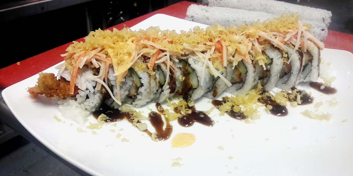 A plate of sushi with sauce and rice.