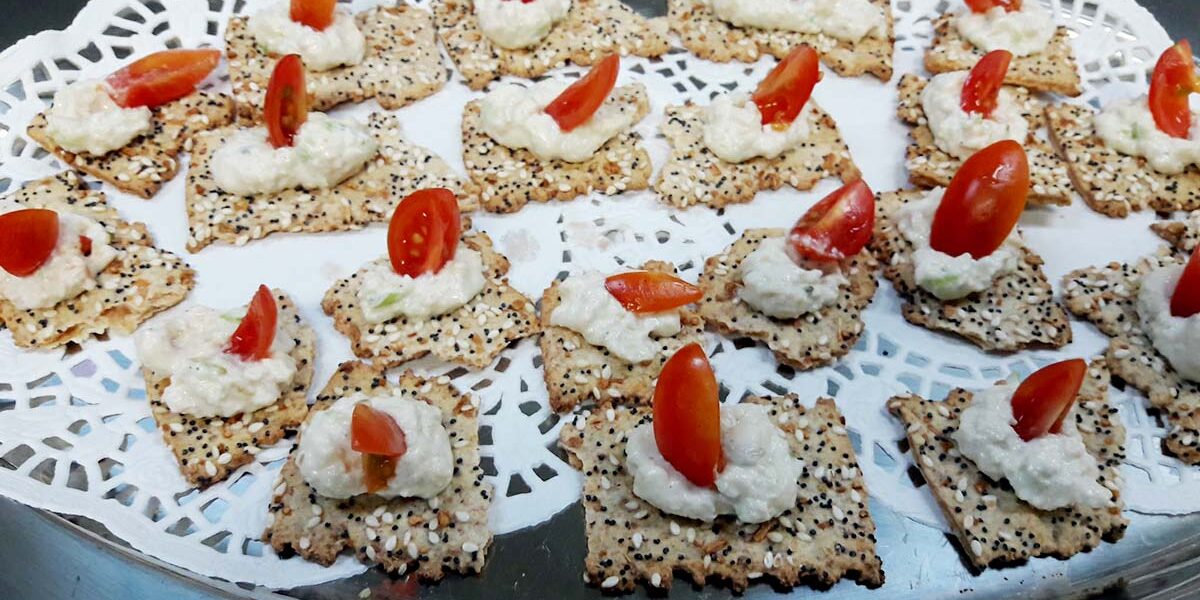 A tray of crackers with cheese and tomatoes on top.