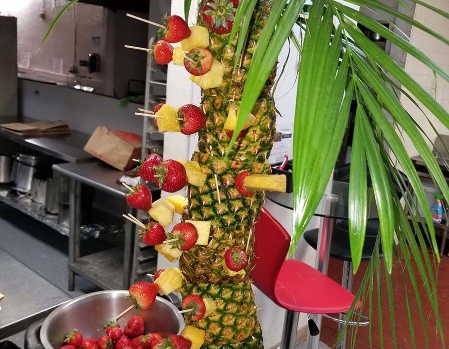 A tall pineapple and strawberry display in the kitchen.