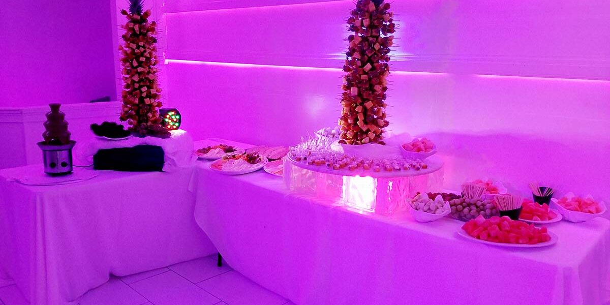 A room with purple lighting and tables of food.