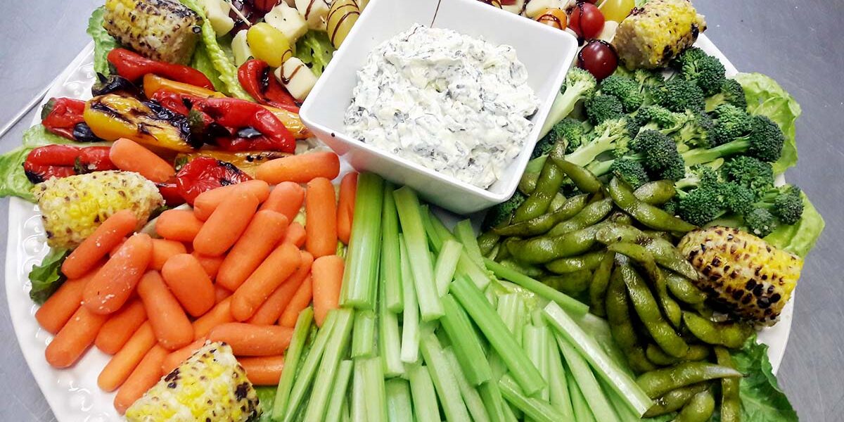 A platter of vegetables with dip on the side.