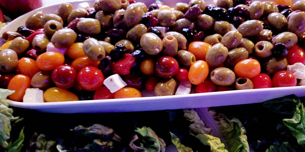 A tray of olives and other vegetables on the table.