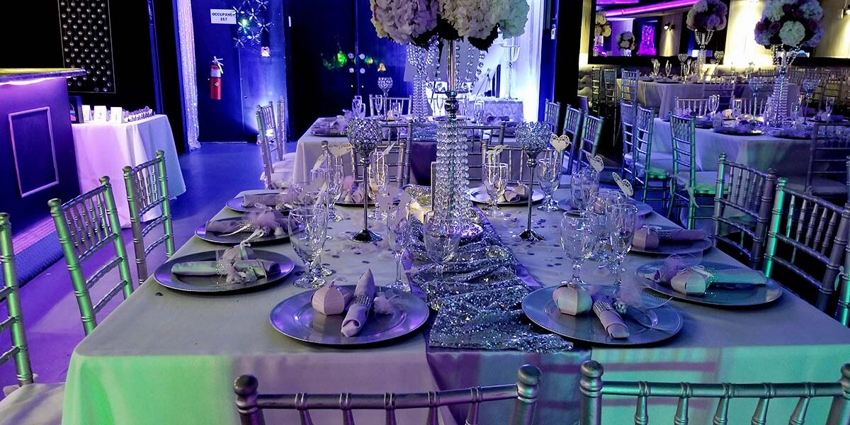 A table set up with silver chairs and purple lighting.