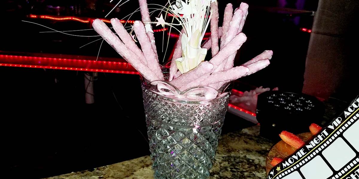 A glass with some pink sticks in it