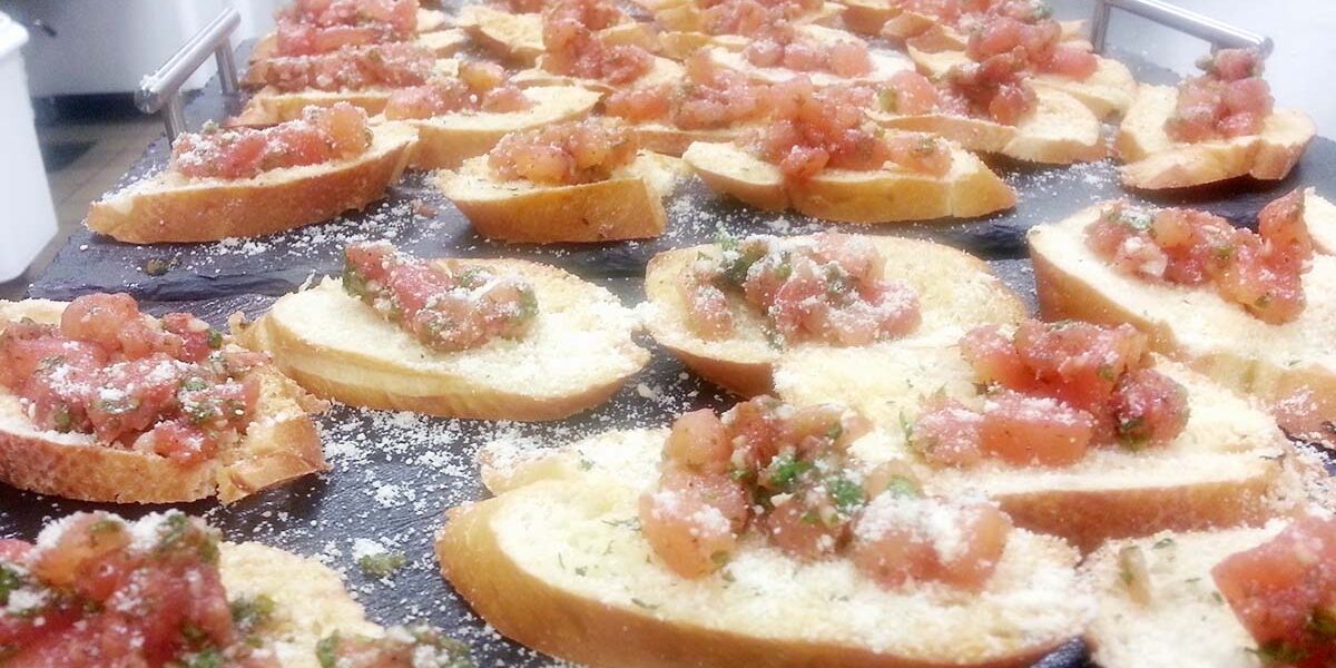 A tray of bruschetta with tomatoes and cheese.