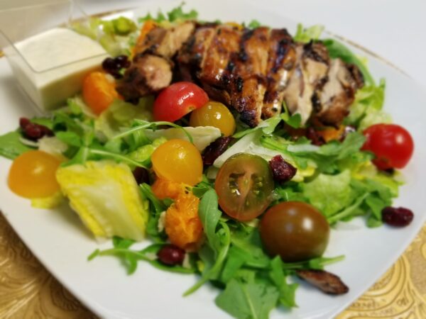 A plate of salad with chicken and tomatoes.