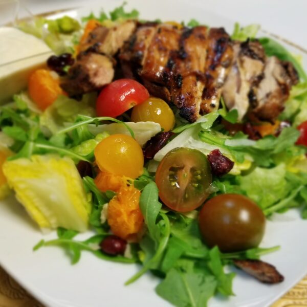 A plate of salad with chicken and tomatoes.