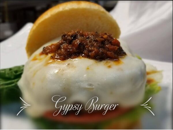 A close up of a burger with cheese and chili