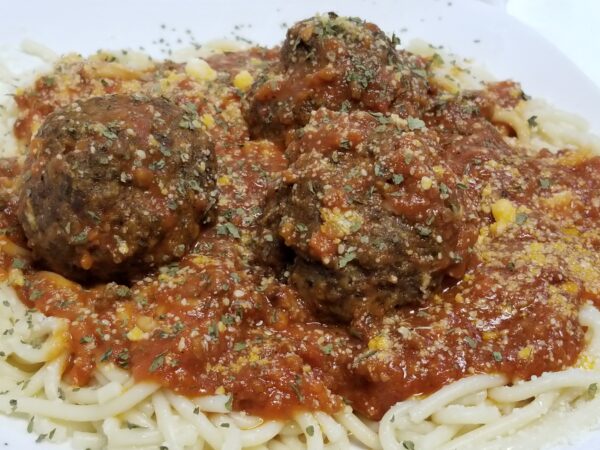 A plate of meatballs and sauce on top of some pasta.