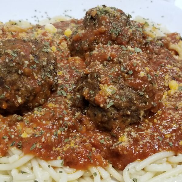 A plate of meatballs and sauce on top of some pasta.