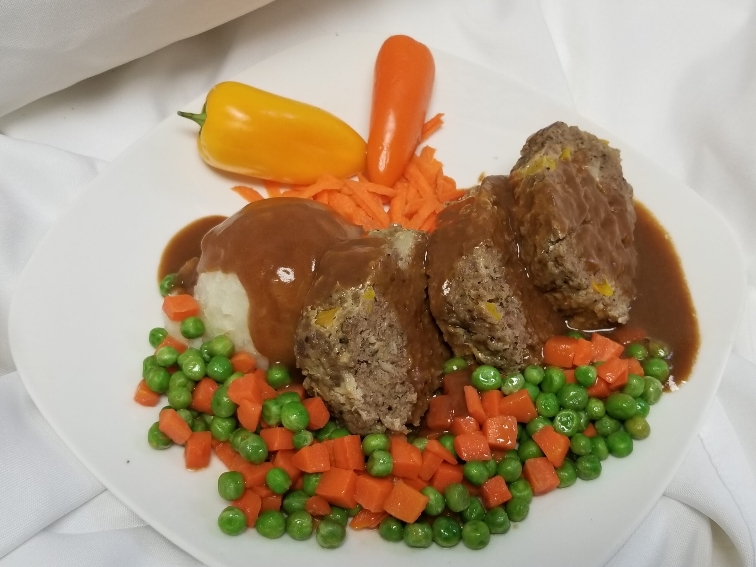 Meatloaf, mashed potatoes, and carrots and peas